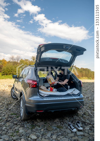 Woman Relaxing in Car Trunk in Nature Woman Relaxing in Car Trunk in Nature 133111505