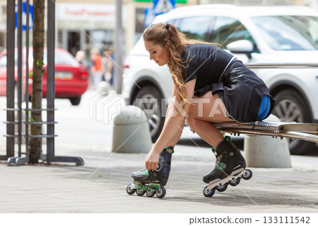 Young woman putting roller skates on Young woman putting roller skates on 133111542