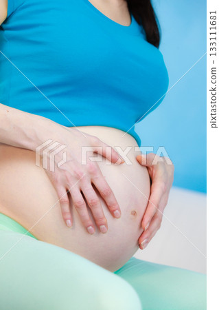 Pregnant woman caressing her belly Pregnant woman caressing her belly 133111681