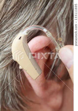Closeup senior woman using hearing aid 133111695