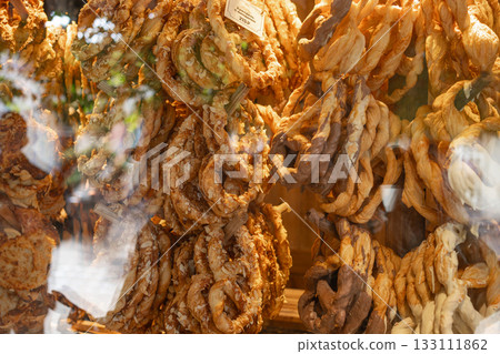 Close-up view of a chocolate-covered pretzel sprinkled with almond pieces, placed inside a shop display. The glossy chocolate coating and crunchy nut texture create an appetizing and inviting visual Close-up view of a chocolate-covered pretzel sprinkled with almond pieces, placed inside a shop display. The glossy chocolate coating and crunchy nut texture create an appetizing and inviting visual 133111862