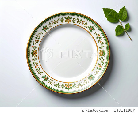 Elegant tableware. Ceramic plate with a green and gold pattern on a white background. Porcelain kitchenware. Close-up. Top view. Elegant tableware. Ceramic plate with a green and gold pattern on a white background. Porcelain kitchenware. Close-up. Top view. 133111997