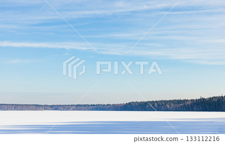 A serene winter landscape features a vast snow covered frozen lake A serene winter landscape features a vast snow covered frozen lake 133112216