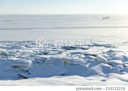 A tranquil winter seascape shows a snow-covered shore with ice floes A tranquil winter seascape shows a snow-covered shore with ice floes 133112218