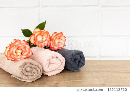 Stack of soft terry towels with rose flowers on the wooden boards 133112730