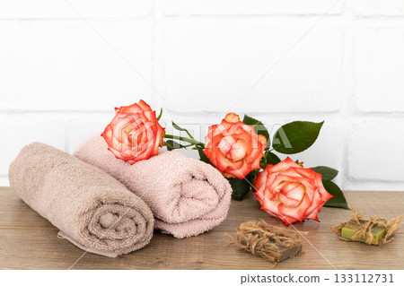 Spa composition with towels, flowers and soap on the wooden boards. Spa composition with towels, flowers and soap on the wooden boards. 133112731
