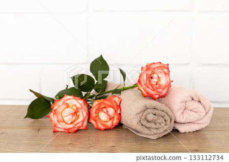 Stack of soft terry towels with rose flowers on the wooden boards 133112734