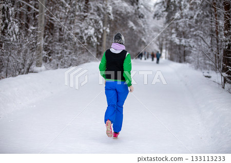 Rear view warmly dressed woman running winter park 133113233