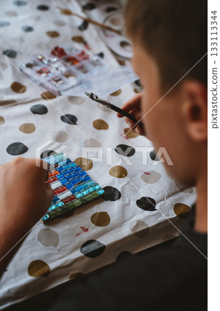 Child Creating Colorful Mosaic with Tiles and Paintbrush Child Creating Colorful Mosaic with Tiles and Paintbrush 133113344