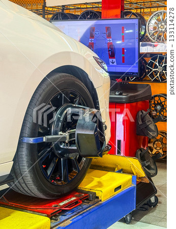 Car wheel alignment on stand with sensors check in service station. Vehicle inside garage workshop for auto camber fixing work, Vehicle inside garage workshop. Car wheel alignment on stand with sensors check in service station. Vehicle inside garage workshop for auto camber fixing work, Vehicle inside garage workshop. 133114278