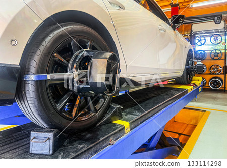 Car wheel alignment on stand with sensors check in service station. Vehicle inside garage workshop for auto camber fixing work, Vehicle inside garage workshop. Car wheel alignment on stand with sensors check in service station. Vehicle inside garage workshop for auto camber fixing work, Vehicle inside garage workshop. 133114298