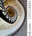 Spiral staircase viewed from above with ornate black railing and warm pendant lights 133114483
