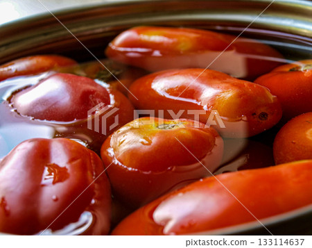 Tomatoes in water in a steel container. A saucepan with tomatoes in water, fresh red vegetables. Tomatoes in water in a steel container. A saucepan with tomatoes in water, fresh red vegetables. 133114637