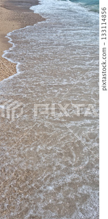 Gentle waves wash over a pebbly beach 133114856