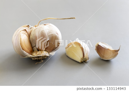Fresh garlic on a grey background, whole bulb and cloves, closeup. Food ingredient Fresh garlic on a grey background, whole bulb and cloves, closeup. Food ingredient 133114943
