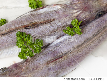 Fresh European hake fish on marble table with parsley, Raw uncooked Merluccius top view 133114946