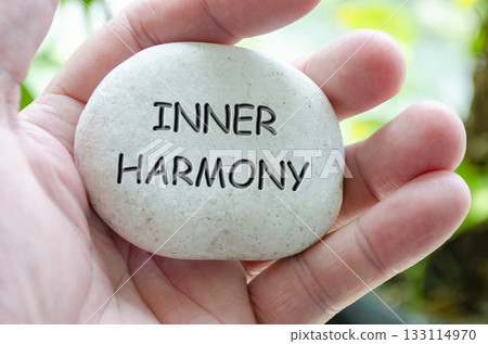 Inner Harmony text engraved on white dark stone with hand holding it. Life harmony concept Inner Harmony text engraved on white dark stone with hand holding it. Life harmony concept 133114970