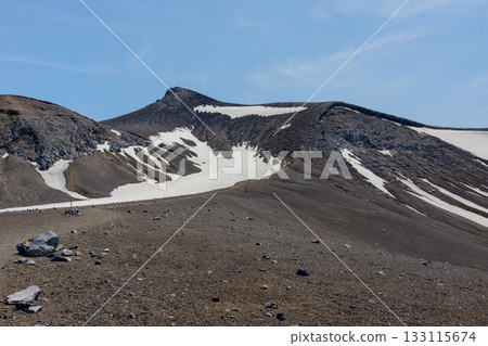 The volcanic landscape of Mount Tokachi, one of Hokkaido's 100 famous mountains, with snow remaining from the hiking trail The volcanic landscape of Mount Tokachi, one of Hokkaido's 100 famous mountains, with snow remaining from the hiking trail 133115674
