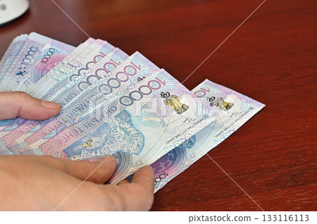 Holding a fan of colorful banknotes in hand during a financial transaction at a local market in the afternoon light Holding a fan of colorful banknotes in hand during a financial transaction at a local market in the afternoon light 133116113