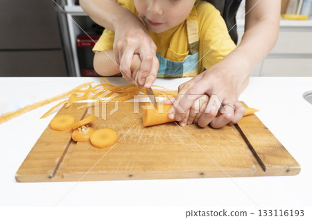 Mother and son cutting carrots together in the kitchen Mother and son cutting carrots together in the kitchen 133116193