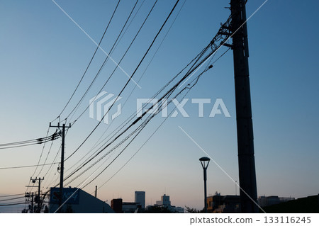 The silhouette of a telephone pole and power lines at dusk 133116245