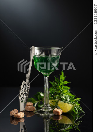 Glass of absinthe with ingredients on a black background. 133116907