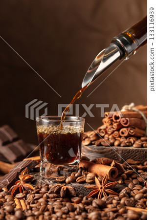 Coffee liquor is poured into a glass. Coffee liquor is poured into a glass. 133116939