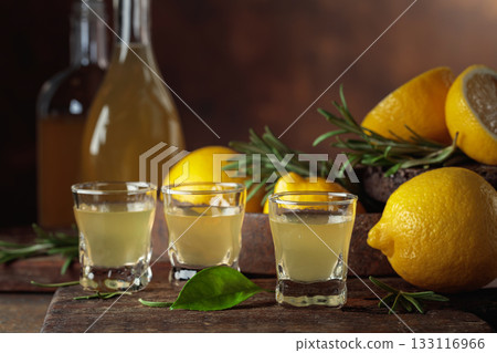 Italian liqueur Limoncello with fresh lemons and rosemary branches. 133116966