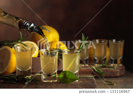 Italian liqueur Limoncello with fresh lemons and rosemary branches. 133116967