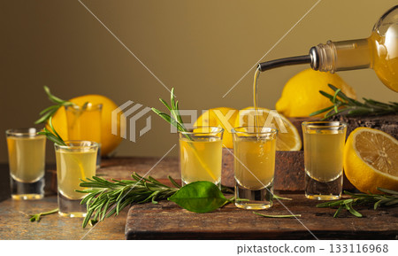 Italian liqueur Limoncello with fresh lemons and rosemary branches. Italian liqueur Limoncello with fresh lemons and rosemary branches. 133116968