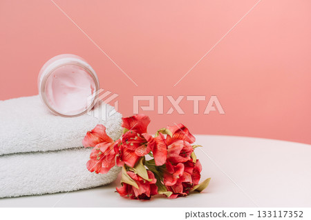 Open cosmetic cream jar on towels with coral flowers background 133117352