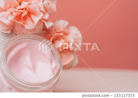 Open pink cream jar with soft carnations 133117353