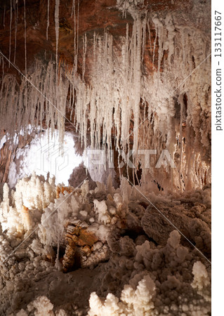 Inside a captivating cave, salt formations hang like icicles, creating a surreal, unique landscape of mineral wonder and natural beauty. Inside a captivating cave, salt formations hang like icicles, creating a surreal, unique landscape of mineral wonder and natural beauty. 133117667