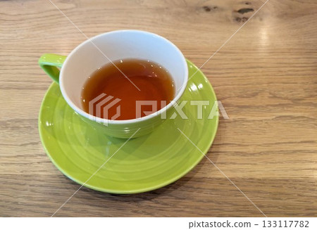 木桌上放著盛茶的青檸茶杯和茶碟。 133117782