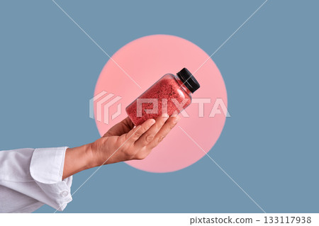 Hand holding bath salts bottle for skincare wellbeing Hand holding bath salts bottle for skincare wellbeing 133117938