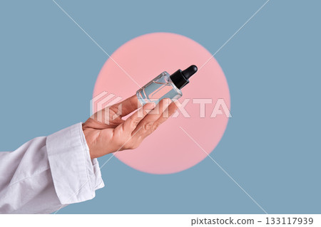 Hand holding cosmetic serum dropper bottle with pipette Hand holding cosmetic serum dropper bottle with pipette 133117939