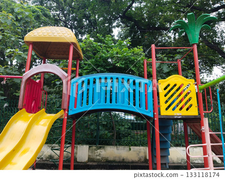 Colorful children playground set with slides, bridge, climbing stairs, swings and canopies in public park, designed for kids recreation, fun and physical activity in a safe and vibrant outdoor Colorful children playground set with slides, bridge, climbing stairs, swings and canopies in public park, designed for kids recreation, fun and physical activity in a safe and vibrant outdoor 133118174