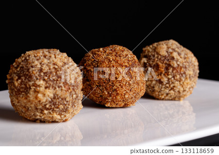 Beautiful candy truffle on a white plate on a black background 133118659