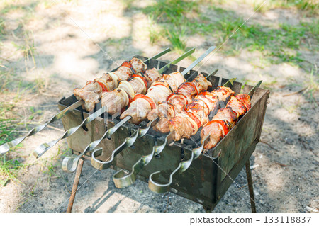 Cooking barbecue with vegetables on skewers. Roasted meat on the grill Cooking barbecue with vegetables on skewers. Roasted meat on the grill 133118837