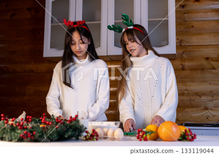girls are preparing festive food in a kitchen with Christmas decorations 133119044