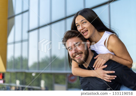 A man carrying a woman on his back through a lush forest trail, 133119058