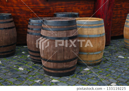 Wooden barrels in rustic setting near cobblestone path on a sunny day Wooden barrels in rustic setting near cobblestone path on a sunny day 133119225
