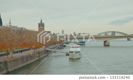 Beautiful autumn scene with boat cruising along river near historic city bridge 133119240