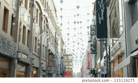 Busy street lined with shops decorated with festive lights during the daytime Busy street lined with shops decorated with festive lights during the daytime 133119275