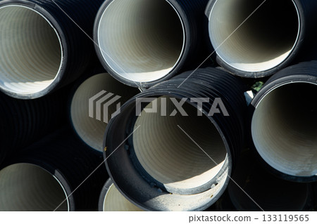 The black drainage pipes are neatly stacked, showcasing smooth interior surfaces and industrial textures, highlighting building materials and engineering design. High quality photo The black drainage pipes are neatly stacked, showcasing smooth interior surfaces and industrial textures, highlighting building materials and engineering design. High quality photo 133119565