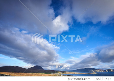 View over the ocean in cloudy blue sky weather with Achill island, Keel vilage and beach View over the ocean in cloudy blue sky weather with Achill island, Keel vilage and beach 133119648