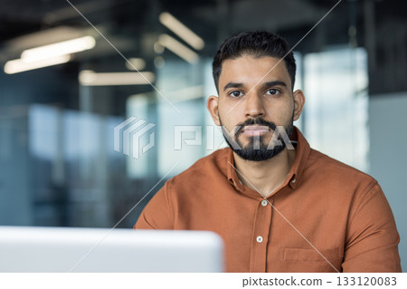 Indian businessman standing in a modern office, looking at camera with serious, confident expression smart-casual entrepreneur conveying professionalism, focus and leadership Indian businessman standing in a modern office, looking at camera with serious, confident expression smart-casual entrepreneur conveying professionalism, focus and leadership 133120083