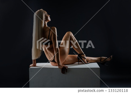 Woman posing elegantly on a pedestal in low light during a creative photoshoot Woman posing elegantly on a pedestal in low light during a creative photoshoot 133120118