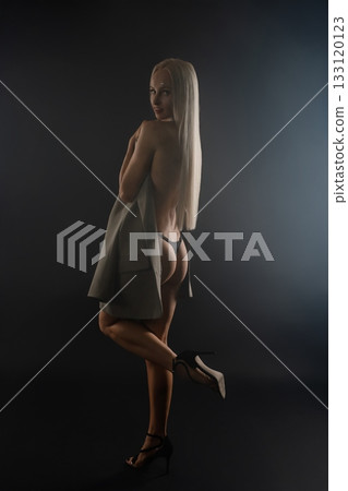 A model poses gracefully in an elegant unequipped outfit in a dimly lit studio A model poses gracefully in an elegant unequipped outfit in a dimly lit studio 133120123