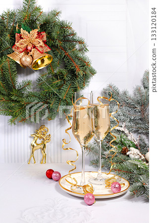 Two glasses of champagne on an elegant festive background with fir branches and decorations, a Christmas Eve concept. Christmas and New Year's mockup for design and product display. Happy New Year Two glasses of champagne on an elegant festive background with fir branches and decorations, a Christmas Eve concept. Christmas and New Year's mockup for design and product display. Happy New Year 133120184